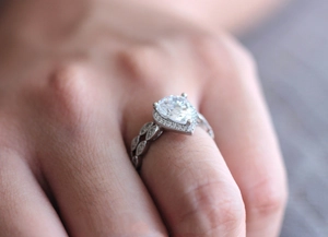 Detalle macro de anillo de compromiso de pera con halo y banda grabada de estilo vintage