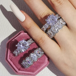 Détail d'un ensemble de bagues de mariée avec pierres taille émeraude et écrin rose