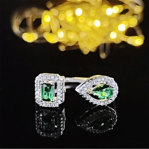 Detailed macro view of an adjustable silver ring with emerald-cut and pear-shaped green stones