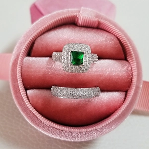 Close-up of luxury emerald-cut green stone ring set in a pink velvet jewelry box