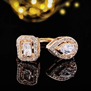 Detailed view of rose gold ring with asymmetrical zircon stones on black mirror