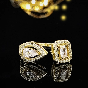 Macro shot of gold double-stone open ring with pear and rectangular zircons on black background