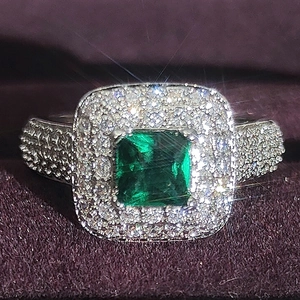 Macro view of square emerald cut gemstone with diamond halo and pavé band detail