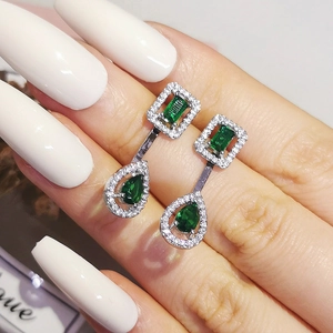 Detailed macro view of vintage emerald-cut and pear-shaped green crystal drop earrings