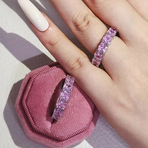 Gros plan de bagues éternité en zircons roses sur la main et dans leur boîte en velours