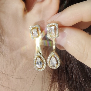 Close-up of luxury gold-plated geometric drop earrings with sparkling clear cubic zirconia