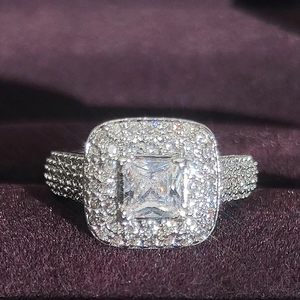 Macro view of a luxury princess cut halo engagement ring on purple velvet background