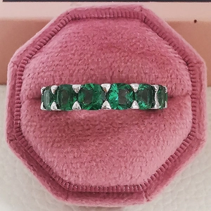 Macro d'une bague en argent sertie de cinq zircons verts ovales dans un écrin rose