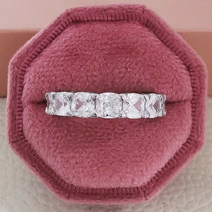 Macro shot of a five-stone cushion-cut engagement ring in a pink velvet hexagon box