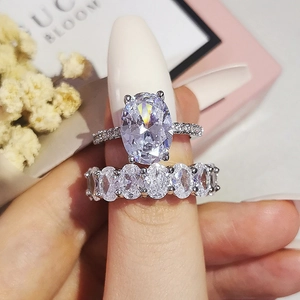 Détail macro du lot de bagues ovales en argent avec pierres claires sur boîte rose
