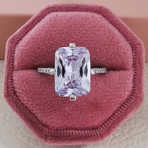 Top view of emerald cut lavender gemstone ring with pave band in pink velvet box