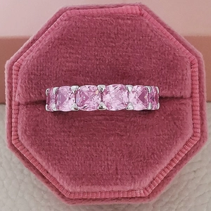 Gros plan sur une bague sertie de pierres roses rectangulaires dans un écrin en velours
