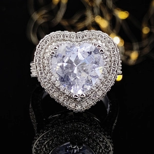 Detailed view of luxury heart-shaped diamond ring with pavé stones on black background