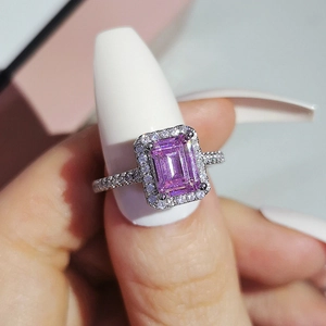 Macro detail of a rectangular emerald-cut pink gemstone ring with halo diamonds