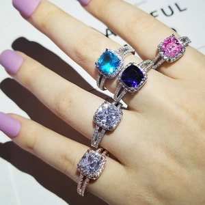 Dettaglio di anelli di lusso con pietre preziose quadrate e pavé di diamanti sulla mano