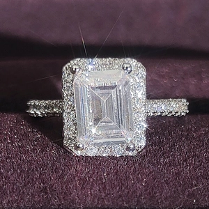 Macro view of emerald cut gemstone ring with sparkling halo and pavé setting details