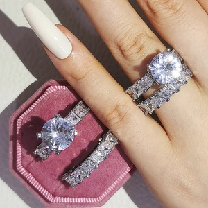Vue macro de bagues de mariage en argent avec diamants ronds et émeraudes dans une boîte rose