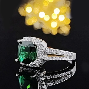 Macro di un anello vintage di lusso con pietra verde taglio smeraldo e pavé di diamanti