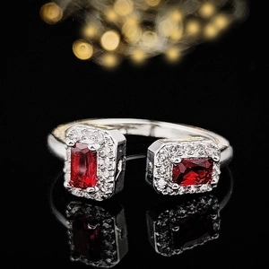 Makroaufnahme von silbernem offenem Ring mit zwei rechteckigen roten Steinen und Diamantrand