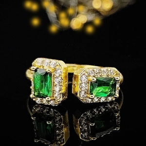 Makroansicht verstellbarer Goldring mit zwei grünen Smaragdschliff-Steinen und Diamanten