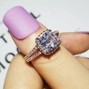Dettaglio anello con zircone taglio cushion in oro rosa con design halo e gambo diviso