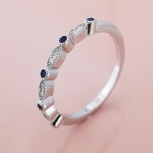 Macro detail van zilveren eeuwigheidsring met blauwe saffieren en milgrain rand