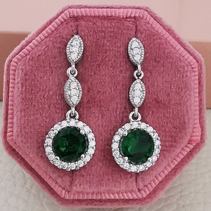 Elegante smaragdgroene druppeloorbellen met zilveren halo diamanten in roze fluwelen doosje