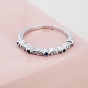 Macrodetail van zilveren ring met afwisselend blauwe saffieren en zirkonia-steentjes