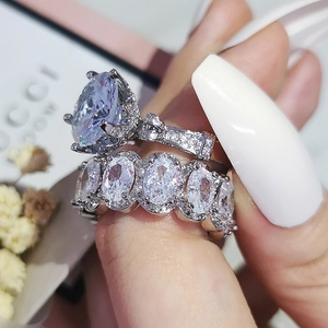 Détail d'un ensemble de bagues de mariage avec grand zircon ovale sur le doigt d'un mannequin