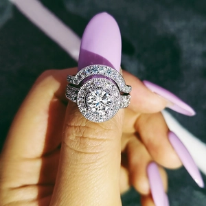 Makroaufnahme eines luxuriösen Halo-Ring-Sets mit Doppeldiamanten und lila Fingernägeln