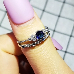 Detailopname van zilveren ringen met blauwe saffiersteen en golvende pavéband