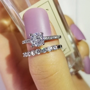 Detalle del anillo de compromiso solitario redondo y alianza pavé en un dedo