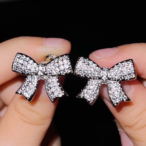 Detail of silver bow earrings with micro-paved cubic zirconia on a dark backdrop