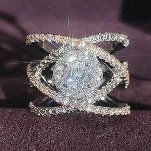 Anello di lusso color argento con grande pietra rotonda e fasce incrociate pavé