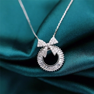 Sparkling bow and wreath pendant necklace with clear zircons on green satin background