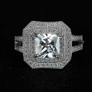 Macro detail of luxury square cushion-cut emerald stone with double halo and paved band