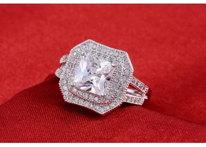 Macro shot of silver ring featuring princess-cut main stone and halo diamond accents