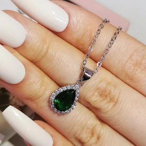 Gros plan d'un collier avec pendentif poire émeraude verte et halo de zircons brillants