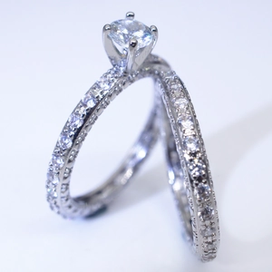 Makroaufnahme von Silber-Ehering-Set mit rundem Zirkonia und Pavé-Besatz auf Weiß