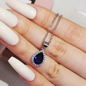 Vue macro d'un pendentif poire en pierre bleue avec sertissage halo sur chaîne argentée