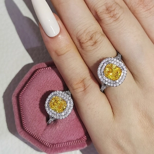 Primer plano de anillo con gema amarilla y doble halo en caja de terciopelo rosa