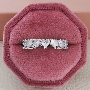 Macro shot of a silver heart-shaped eternity ring in a pink velvet jewelry box