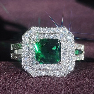 Luxurious emerald cut green stone ring with double halo diamond accents in silver finish