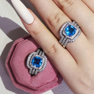 Detail of luxury cushion cut blue sapphire ring set with halo pavé diamonds on finger