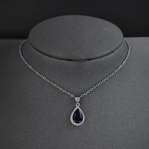 Détail du collier avec pierre bleu foncé en forme de poire et chaîne argentée sur mannequin