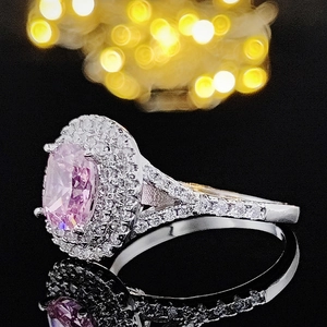 Vista macro lateral de un anillo de lujo con gema rosa ovalada y pavé de diamantes