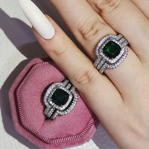 Detail of luxury ring set featuring square green gemstones and pave crystals in a gift box