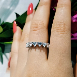 Close-up of heart-shaped cubic zirconia wedding ring on a finger with floral background