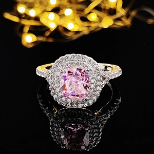 Detalle de anillo con gema rosa de corte cojín y banda bicolor con pavé de diamantes