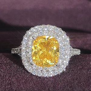 Primer plano de anillo de lujo con piedra amarilla corte cojín y doble halo plateado